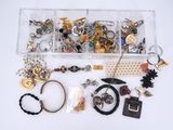 an assortment of assorted jewelry in a clear box on a white surface
