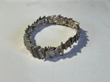 bracelet en argent orné de pointes sur un fond blanc