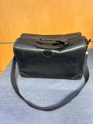 un vieux sac à main noir posé sur une table bleue