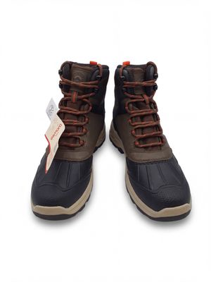 une paire de bottes marron et noires avec des lacets marron sur fond blanc