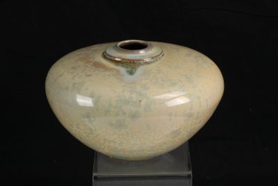 un vase posé sur un socle, sur un fond noir