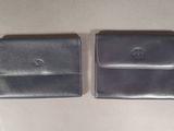 two black leather wallets sitting next to each other on a table