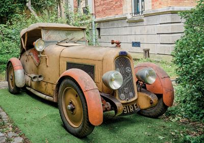 une vieille voiture garée sur la pelouse devant un immeuble