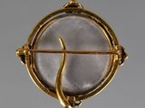 an image of a gold and white broochle with a snake on it