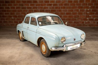 a blue car that is parked in front of a brick wall