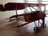 un petit avion rouge posé par terre devant une porte
