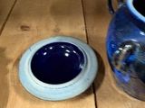 a blue vase sitting on a wooden table next to a blue bowl
