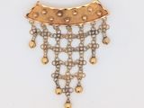 un gros plan d'un collier en or et diamants posé sur une surface blanche