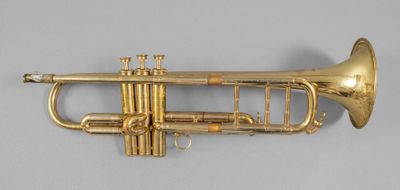 an antique brass trumpet with a brass bell on a gray background