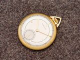 une montre de poche en or posée sur un tapis marron