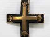 a close up of a black and gold cross on a white surface