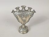 un vase ancien en argent posé sur une surface blanche, avec un fond blanc