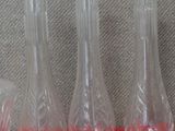 quatre vases en verre posés sur une surface rouge