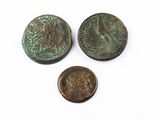 trois pièces de monnaie romaines antiques et un penny posés sur une surface blanche