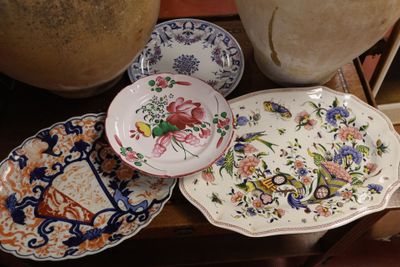de nombreuses assiettes et bols posés sur une table, avec un vase en arrière-plan