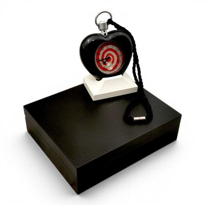 une horloge en forme de cœur posée sur un coffret noir, avec un porte-clés