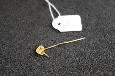 un gros plan d'une broche en or à laquelle est accrochée une étiquette
