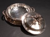a silver plate with a lid on a black table