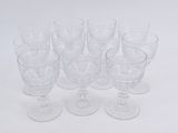 six clear glass cups and one empty glass cup on a white surface