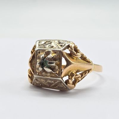 Gros plan sur une bague en or ornée d'une pierre verte