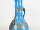 a blue and gold vase sitting on a white surface