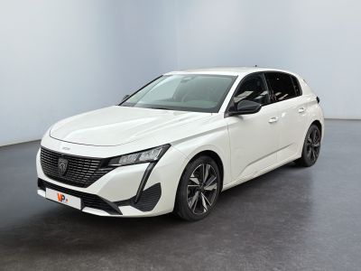 Une voiture blanche est garée dans une pièce blanche au sol noir.