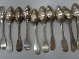 many spoons and forks lined up on a table