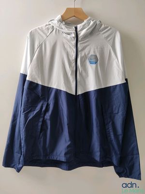 une veste coupe-vent blanche et bleue accrochée au mur