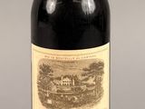 une bouteille de vin rouge sur fond gris, avec un bouchon rouge