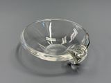 a clear glass bowl with a metal handle on a table