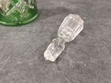 a green glass bottle and a clear glass bottle on a table