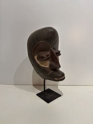 an image of a wooden mask on a stand on a white surface