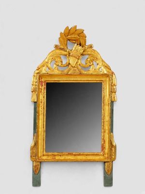 un miroir avec un cadre doré sur un mur blanc