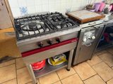 a stainless steel stove with a red burner in a kitchen