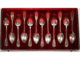 six cuillères dans un étui en velours rouge posé sur une surface blanche