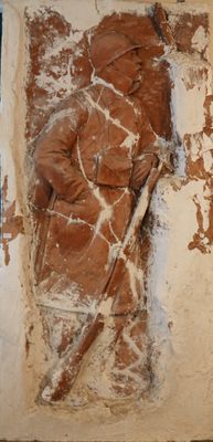 une statue représentant un homme tenant un bâton, accrochée à un mur