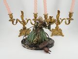une figurine représentant une femme tenant un candélabre orné de bougies roses