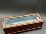 an old wooden box with a glass lid on a table