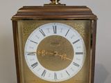 a small wooden clock with roman numerals on the face
