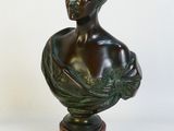 statue représentant le buste d'un homme, posée sur un socle en bois, sur fond blanc