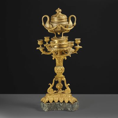 a gold plated teapot on a stand with a cup and saucer