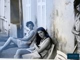 deux femmes assises sur un banc devant un immeuble