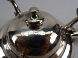 a silver tea pot with a handle on a white table