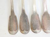 six cuillères sont alignées sur une surface blanche