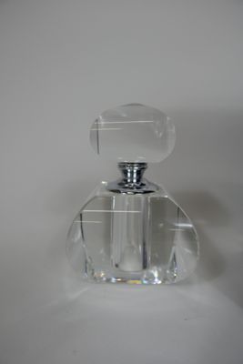 a clear glass bottle with a silver top sitting on a white surface