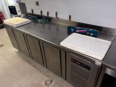 plan de travail en acier inoxydable dans une cuisine professionnelle, équipé d'un évier et d'un réfrigérateur
