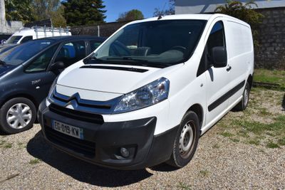 une camionnette blanche garée dans un parking à côté d'autres voitures
