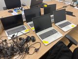 quatre ordinateurs portables posés sur une table, entourés de câbles