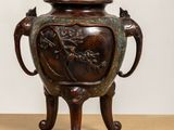 an image of a bronze vase sitting on top of a wooden table