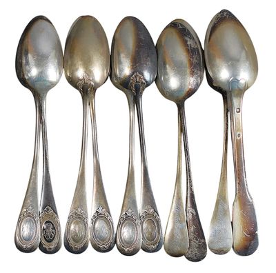 six cuillères en argent sont alignées sur une surface blanche